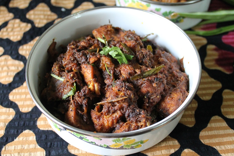 spicy pepper chicken served in a white serving dish with coriander leaves on top