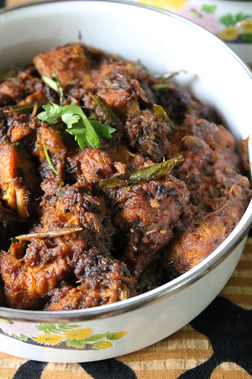 spicy pepper chicken served in a white serving dish with coriander leaves on top