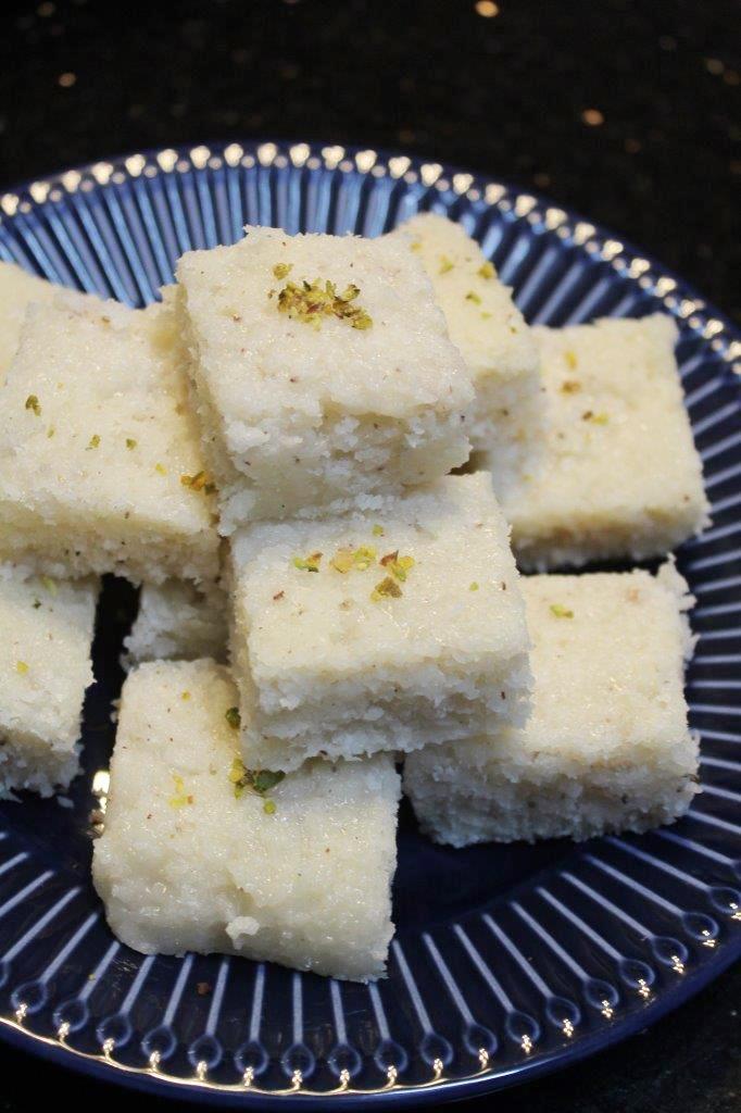 coconut barfi stacked on a blue plate