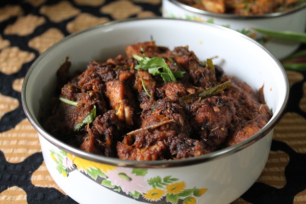 spicy pepper chicken served in a white serving dish with coriander leaves on top