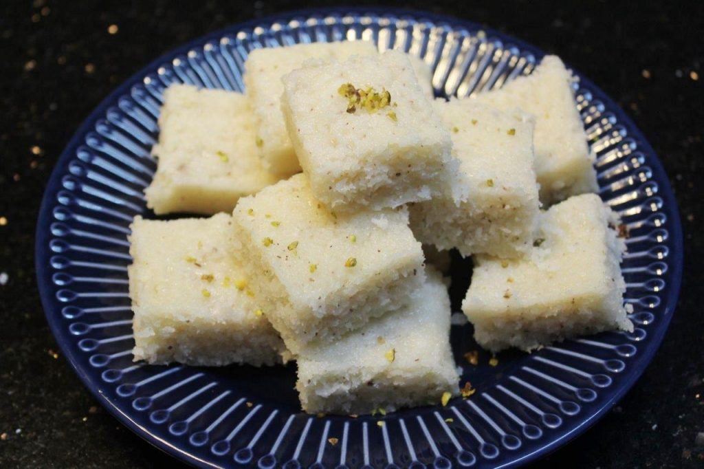 coconut barfi stacked on a blue plate