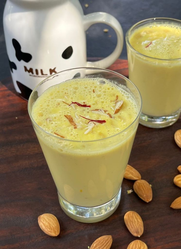 chilled badam milk garnished with chopped nuts and saffron