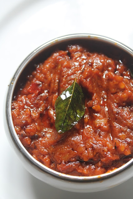 tomato chutney served in a bowl with a fried curry leaves on top