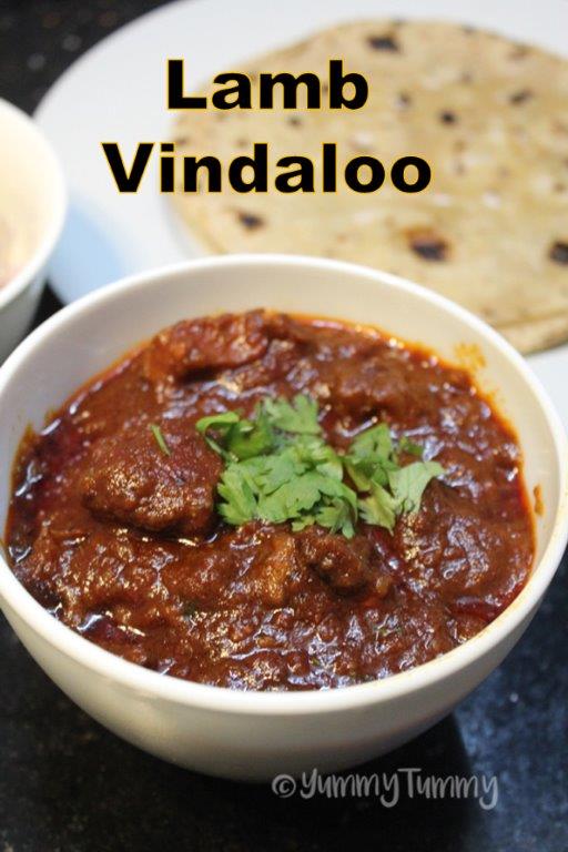 top shot of lamb vindaloo served with roti in a white bowl with coriander leaves for garnishing