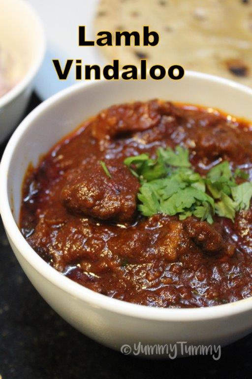 lamb vindaloo served with roti in a white bowl with coriander leaves for garnishing