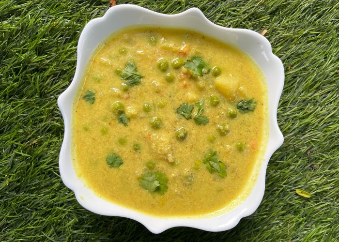 Aloo Kurma served on a white bowl with coriander leaves garnish