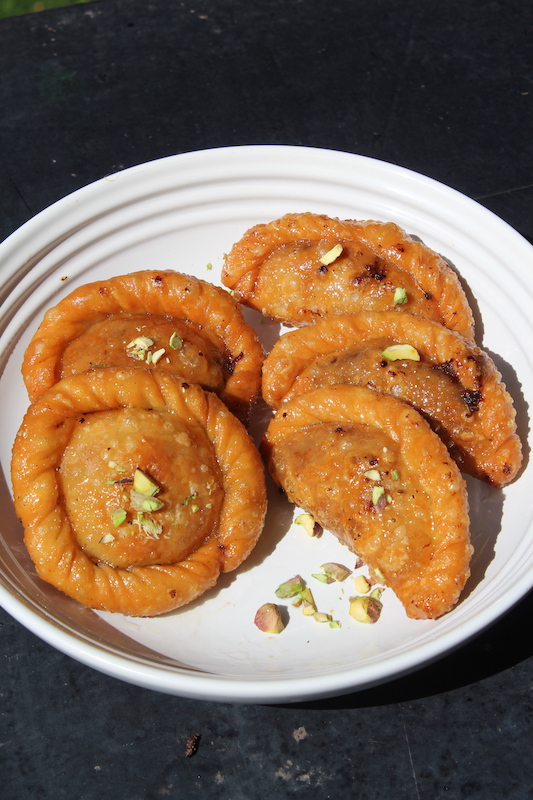 Top angle of Suryakala Chandrakala Sweet served in a white plate topped with chopped nuts