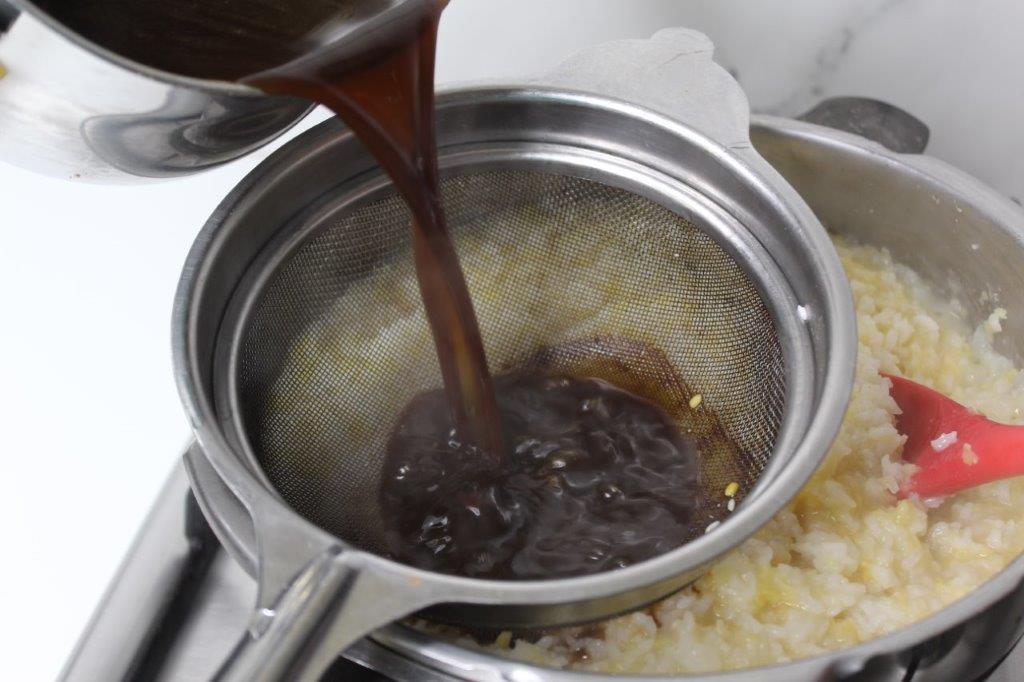 strain jaggery syrup into the cooked rice for making sweet pongal | sakkarai pongal