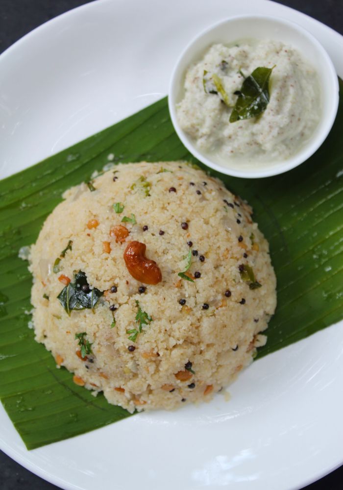 close up shot of upma served in banana leaf with coconut chutney