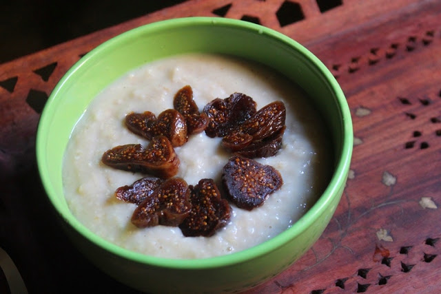 creamy oats porridge served in a green bowl with sliced figs on top