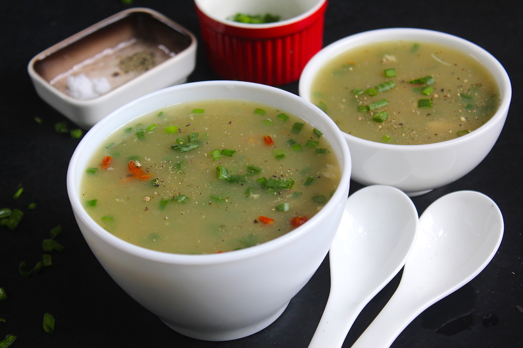 chicken clear soup served in a soup bowl chinese style with spring onions garnish.