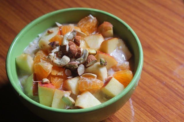 creamy oats porridge served with chopped apples, oranges and dried nuts