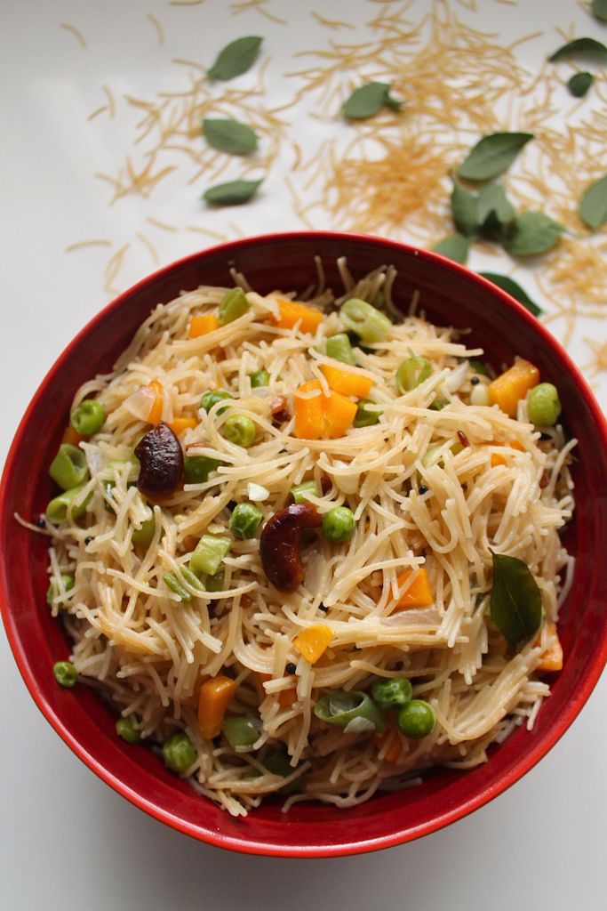 semiya upma served in a red bowl with fried cashews on top