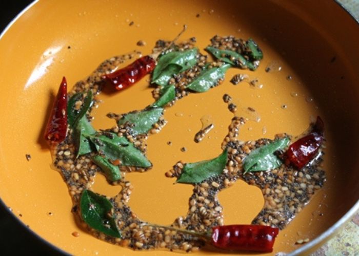 tempering whole spices in hot oil for making semiya upma