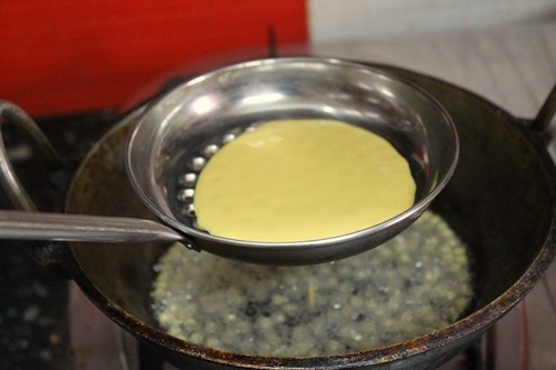 pour gram flour batter in boondhi karandi 