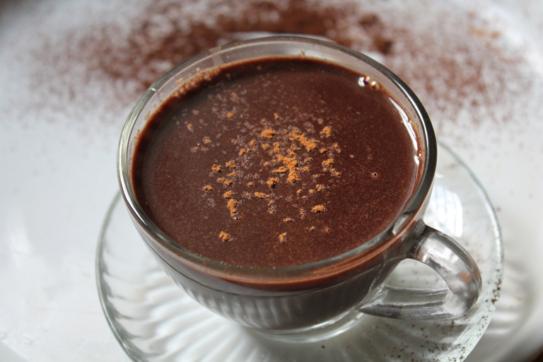 rich hot chocolate served in a glass cup with a sprinkle of cocoa powder on top 