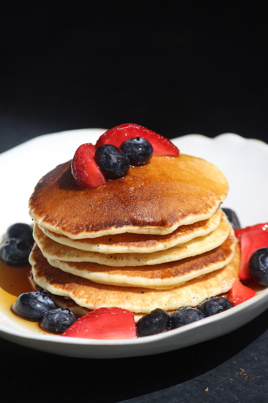 stack of pancakes served with berries on a white plate