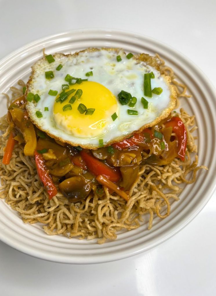 american chop suey - fried noodles topped with sauce and fried egg