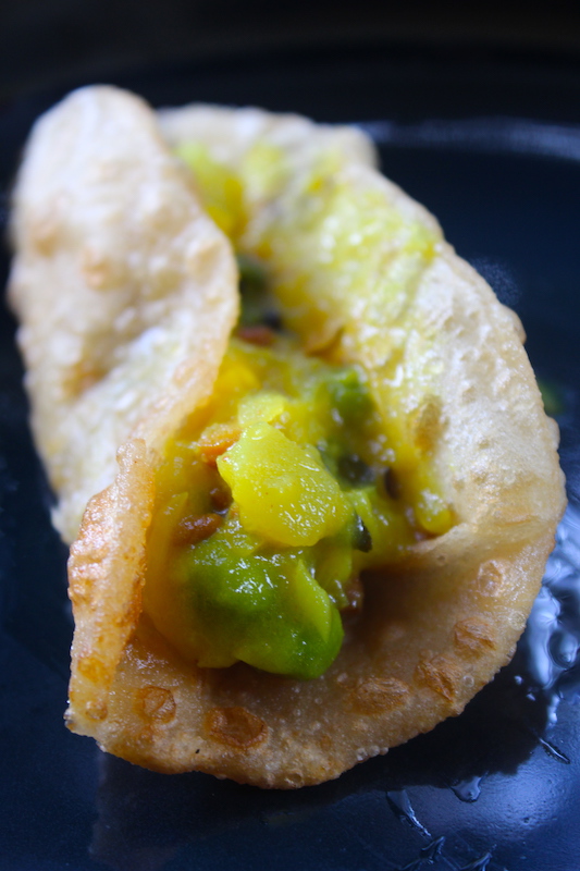 potato masala piled over poori which is folded into a taco shape