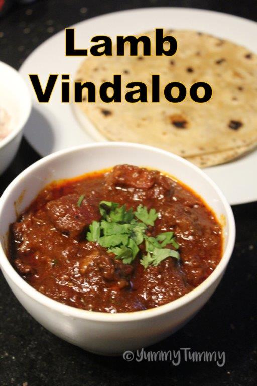 lamb vindaloo served with roti in a white bowl with coriander leaves for garnishing