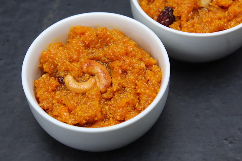 carrot halwa served in a white bowl with fried cashews on top for garnishing