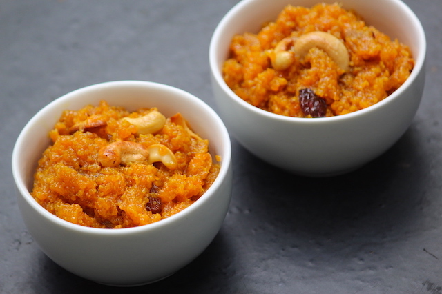 carrot halwa served in a white bowl with fried cashews on top for garnishing