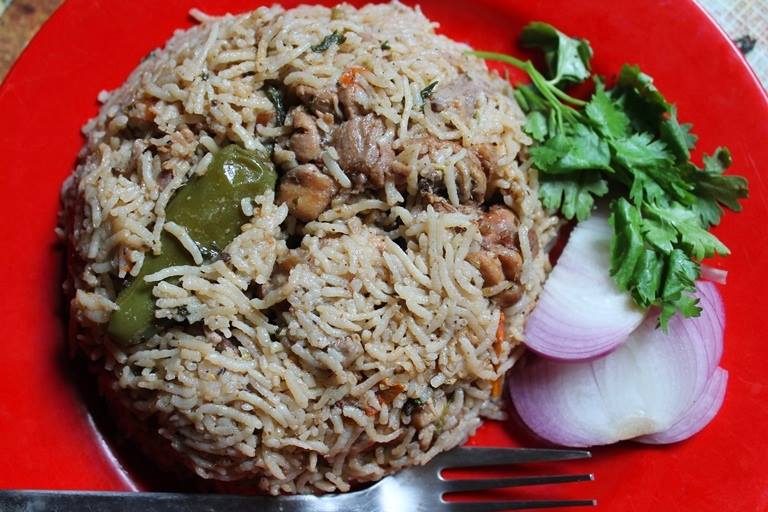 chicken pulao served with sliced onions and coriander leaves