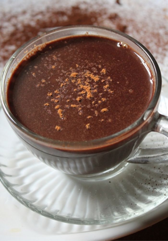 rich hot chocolate served in a glass cup with a sprinkle of cocoa powder on top 