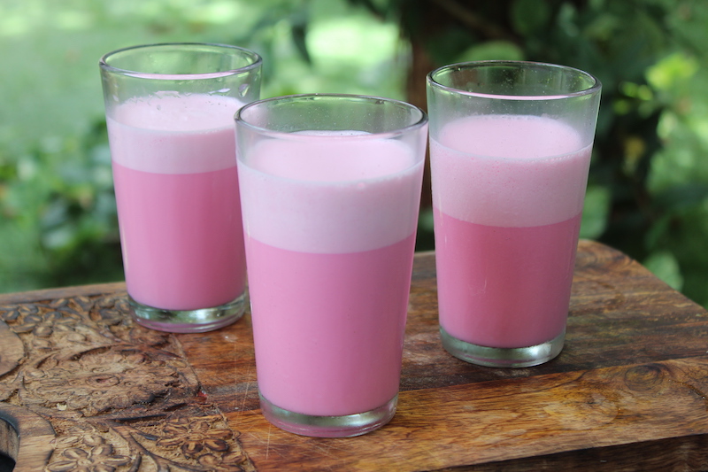 three glasses of rose milk served on a summer day in a wooden platter