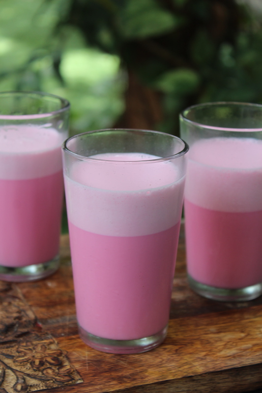 three glasses of rose milk served on a summer day in a wooden platter