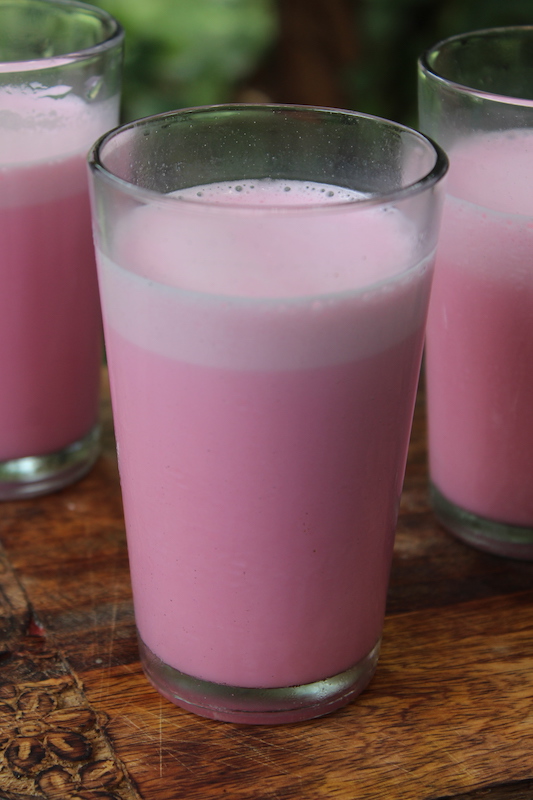 three glasses of rose milk served on a summer day in a wooden platter