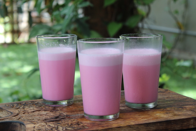 three glasses of rose milk served on a summer day in a wooden platter