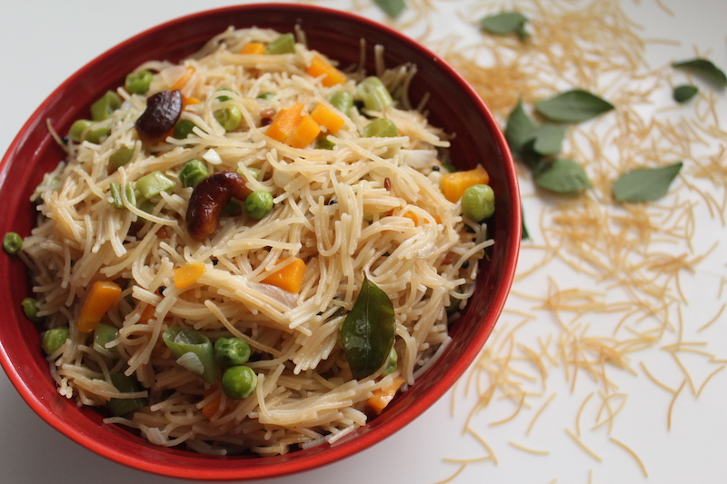 semiya upma served in a red bowl with fried cashews on top