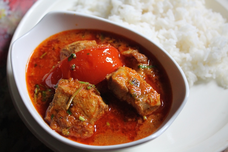 fish curry served in a white bowl with steamed rice