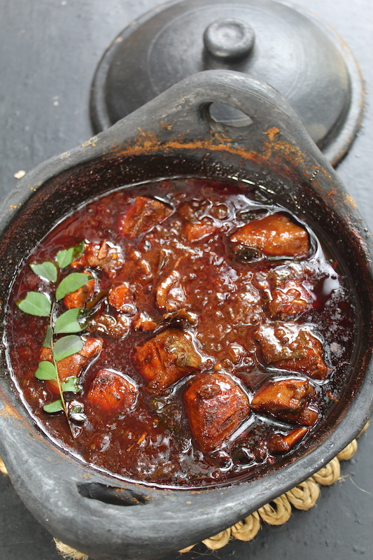 kerala meen curry made and served in clay pot with a sprig of curry leaves 