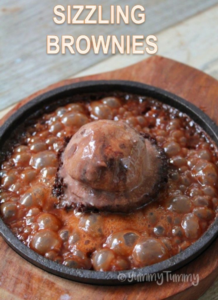 close shot of brownie served with ice cream and chocolate sauce in sizzler plate