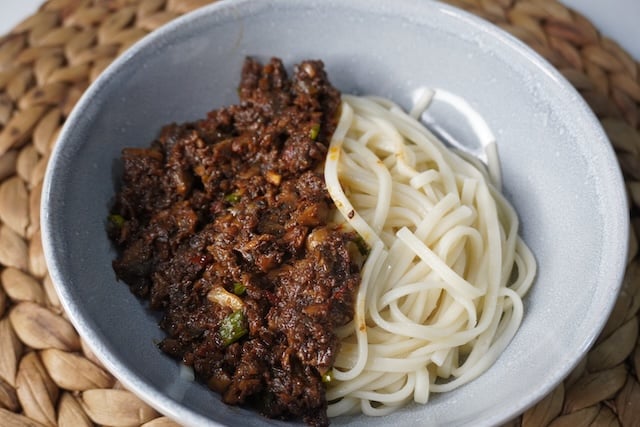 take noodles and mushroom topping in a bowl